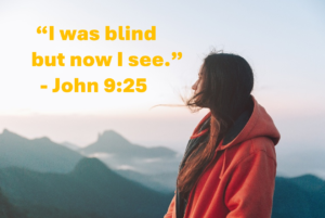 John 925 | Fountain of Life Quote: 'I was blind but now I see.' John 9:25 over a person in an orange hoodie gazing at mountains at sunset.